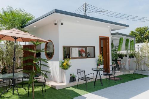 una casa blanca con una mesa y sillas y una sombrilla en Space Water House พูลวิลล่าครอบครัว, en Ban Pong