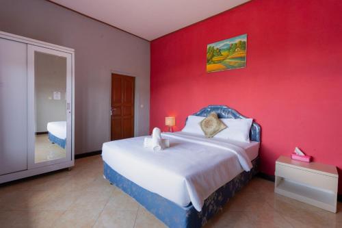 a bedroom with a large bed with a red wall at Mountain View House Kintamani in Kintamani