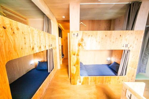 two bunk beds in a room with wooden walls at momodani agito 桃谷アジト in Osaka