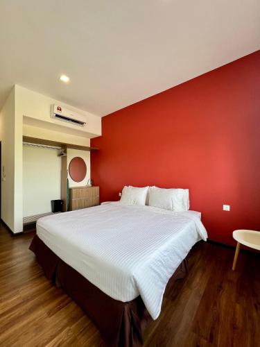 a bedroom with a large bed with a red wall at Roxy Sematan Beach Townhouse Deluxe 7 ,8 ,9, 10 ,11 ,12 in Sematan
