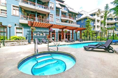 a swimming pool with two chairs and a building at Alpenglow Lodge Rainbow Look Out Studio by MVA in Whistler