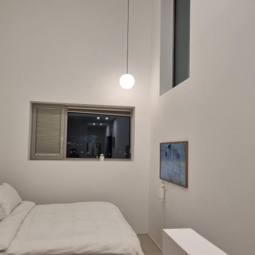 a white bedroom with a bed and a window at Laon on 37 in Tongyeong
