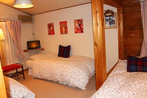 a bedroom with two beds and a tv in it at 一棟貸し 露天風呂付き Snowfall Meteor in Kaminoyama