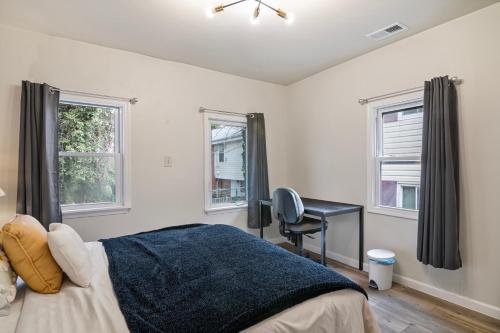 a bedroom with a bed and a desk and two windows at USNA Home In Downtown Annapolis in Annapolis