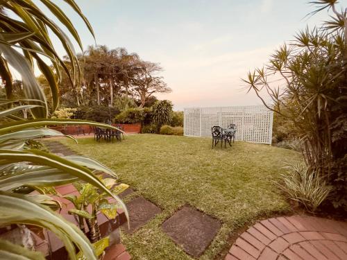 a garden with tables and chairs on the grass at Ridgeview Lodge in Durban