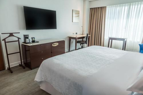 a hotel room with a bed and a flat screen tv at Sheraton Guayaquil in Guayaquil