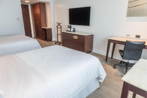 a hotel room with two beds and a desk and a television at Sheraton Guayaquil in Guayaquil