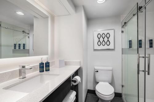 Four Points by Sheraton Greensboro Airport في جرينسبورو: حمام أبيض مع مرحاض ومغسلة