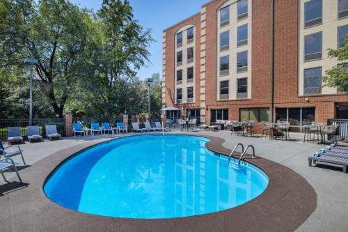 a large swimming pool with chairs and a building at Four Points by Sheraton Greensboro Airport in Greensboro