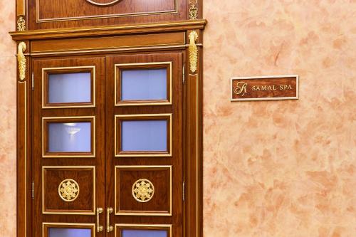 a wooden door with a clock on a wall at Kainar Hotel in Shymkent