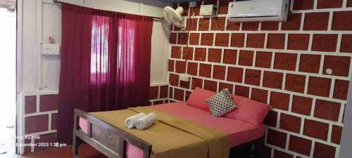 a bedroom with a brick wall and a bed with pink pillows at Casa Beach hut Resort in Palolem