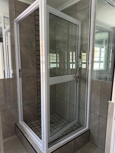 una cabina doccia con porte in vetro in un bagno di The Zebra a Gqeberha