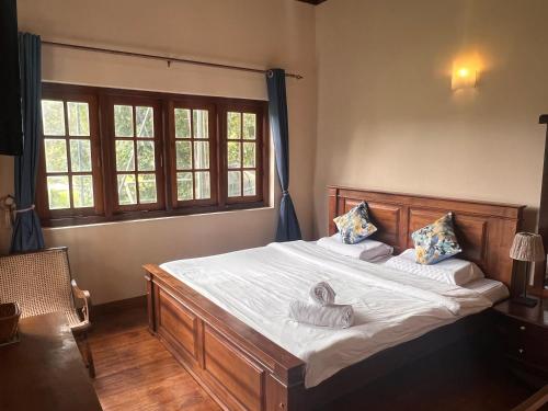 a bedroom with a large bed with white sheets and pillows at Lakeside Garden Bungalow 湖畔花园山居 in Nuwara Eliya