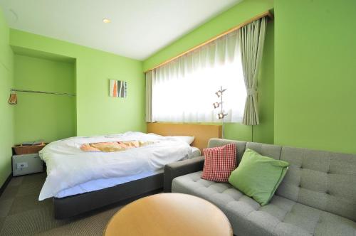 a bedroom with a bed and a couch and a window at KKR Suwakoso in Suwa