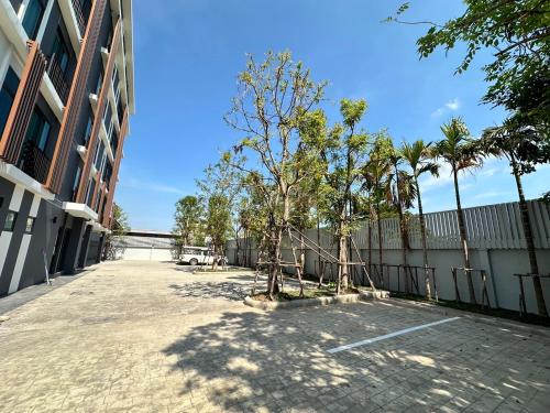 a courtyard of a building with trees and a fence at BB HOUSE Rangsit in Ban Talat Rangsit