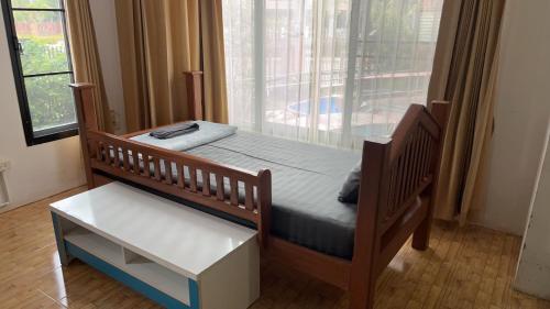 a bedroom with a wooden bed and a window at บ้านสวนรัญจวนสาขาสุราษฎร์ธานี in Ban Huai Chiat