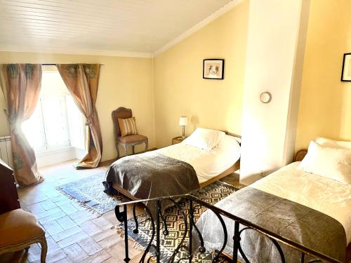 a bedroom with two beds and a window at Villa das Vinhas in Aldeia Galega da Merceana
