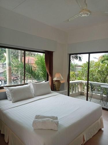 a bedroom with a large white bed and a large window at Garden Home Kata in Kata Beach