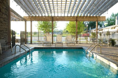 a swimming pool with chairs and a pergola at TownePlace Suites by Marriott Lafayette South in Lafayette
