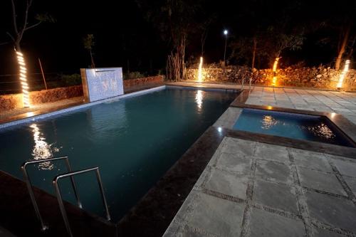 a swimming pool at night with lights in it at Mango Farm Resort in Udaipur