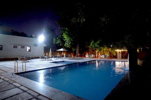 a swimming pool at night with chairs and lights at Mango Farm Resort in Udaipur
