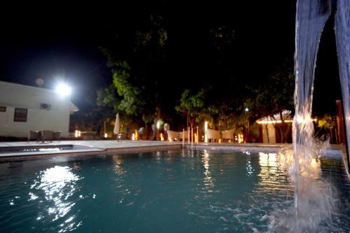 a water fountain in a pool at night at Mango Farm Resort in Udaipur