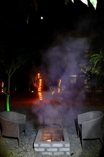 a fire pit with smoke in a yard at night at Mango Farm Resort in Udaipur