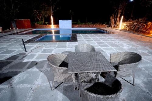 a patio with a table and chairs next to a pool at Mango Farm Resort in Udaipur