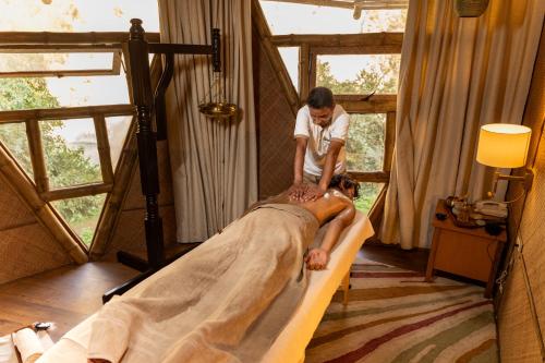 a woman laying on a bed in a room at ONENESS Rishikesh by Ganga Kinare - A Luxury Wilderness Resort in Rishīkesh