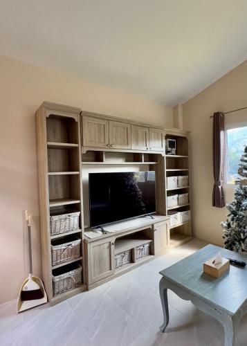 a living room with a large entertainment center with a flat screen tv at Flora Prairie at Mae Rim, Chiang Mai in Ban Tai