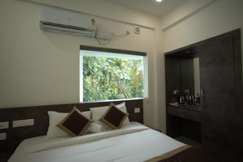 ein Schlafzimmer mit einem weißen Bett mit einem Fenster in der Unterkunft Sreeja Myst in Athirappilly