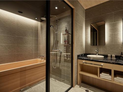 a bathroom with a shower and a sink and a tub at One Station Hotel Kumamoto -DLIGHT LIFE & HOTELS- in Kumamoto