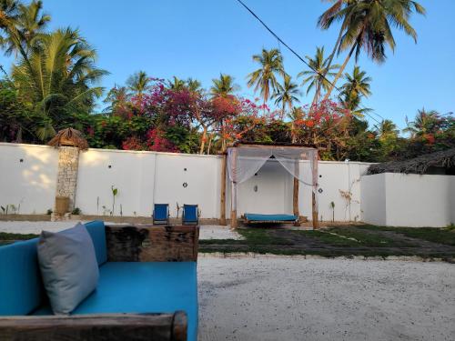 a blue couch in front of a white fence at Mambo Cabana in Pwani Mchangani