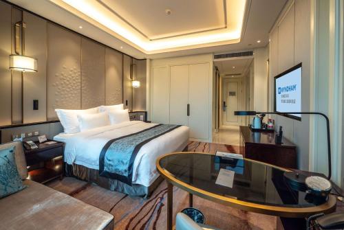 a hotel room with a bed and a table at Wyndham Qingdao l Free Fixed-Time Shuttle Service Between Hotel and Airport & North Railway Station l Outdoor Children's Amusement Park l 1-Hour Play Snooker or Table Tennis in Qingdao