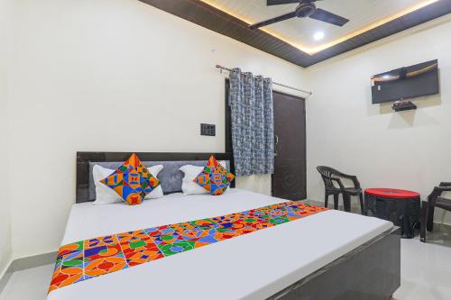 una camera da letto con un grande letto bianco con cuscini colorati di FabExpress Awadh Inn - 400m from Shri Ram Janam Bhumi a Ayodhya