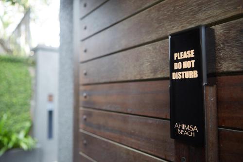 a sign on a wooden wall that says please do not disturb at Ahimsa Beach in Jimbaran