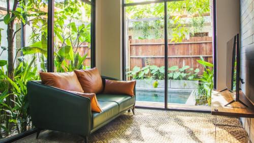 a green couch in a living room with a large window at Takak Villas in Siem Reap