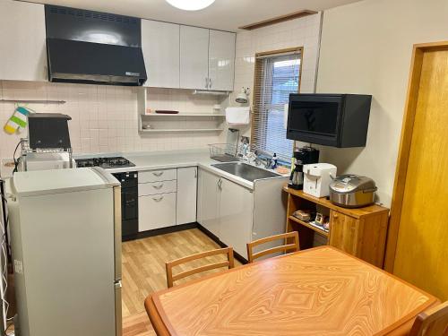 a small kitchen with a table and a refrigerator at ユーカラ屋 in Nanae