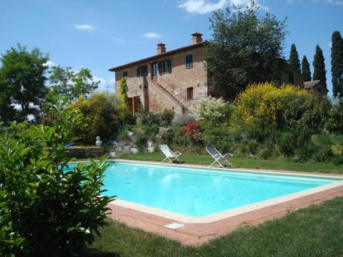 a swimming pool with two chairs in front of a house at Al Giardino Degli Etruschi in Chiusi