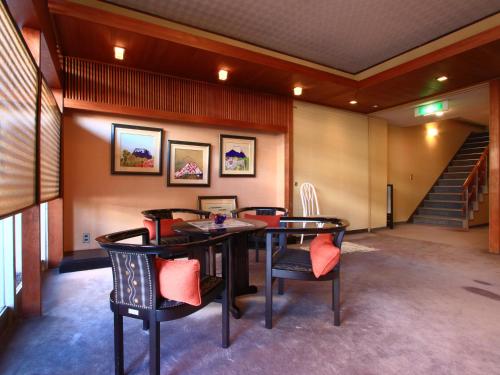 a room with a table and chairs and a staircase at 割烹旅館小川荘 in Ōmiya