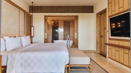 a bedroom with a bed and a tub and a television at AYANA Segara Bali in Jimbaran