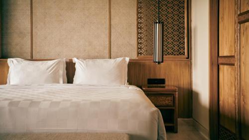 a bedroom with a bed with white sheets and pillows at AYANA Segara Bali in Jimbaran