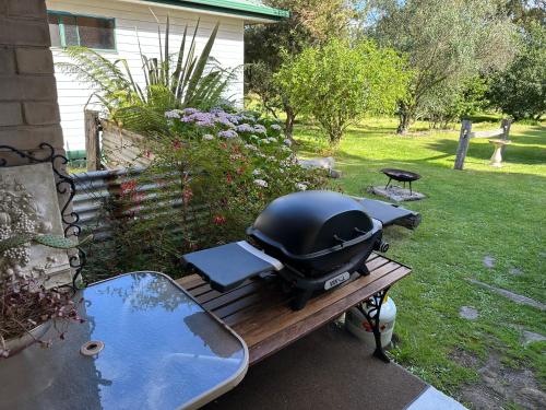 a grill sitting on a picnic table in a yard at Bush Retreat Farm Stay 1BR Guest Suite in Alberton West