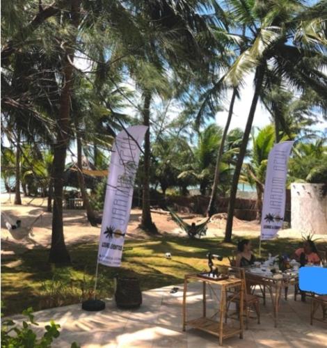 a person sitting at a table on a beach with trees at Oasis em Praia Azul in Pitimbu