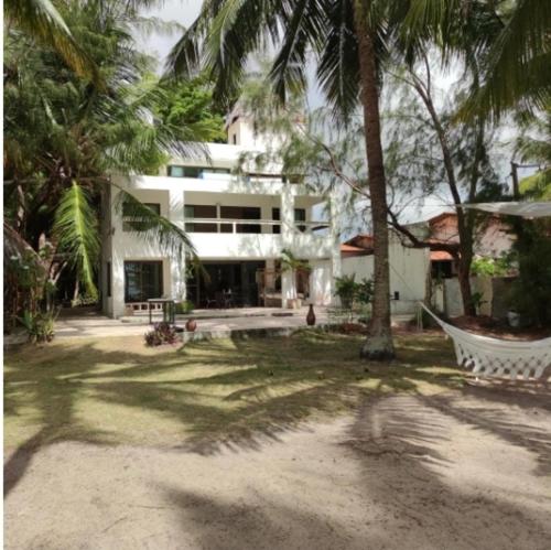 a house with palm trees and a hammock in a yard at Oasis em Praia Azul in Pitimbu