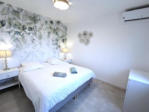 a bedroom with a white bed with a flowery wall at Gîte - Chez Gabriel et Julie in Viviers