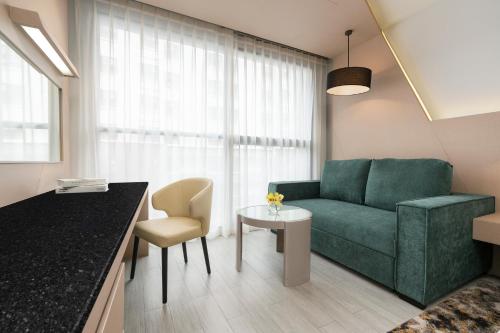 a living room with a green couch and a table at Hyatt Place Bangkok Sukhumvit 1 in Bangkok