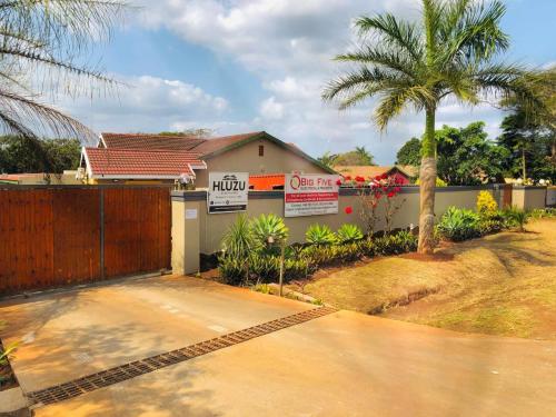 a house with a fence and a palm tree at Hluzu Guest House in Hluhluwe