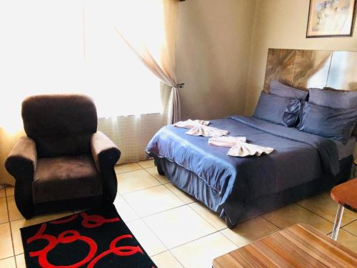 a bedroom with a bed and a chair at Hluzu Guest House in Hluhluwe