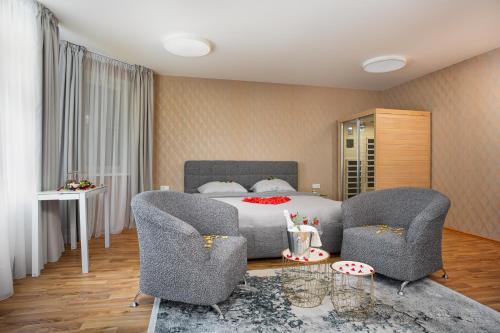 a bedroom with a bed with two chairs and a table at Penzion Solid Spa in Mladá Boleslav